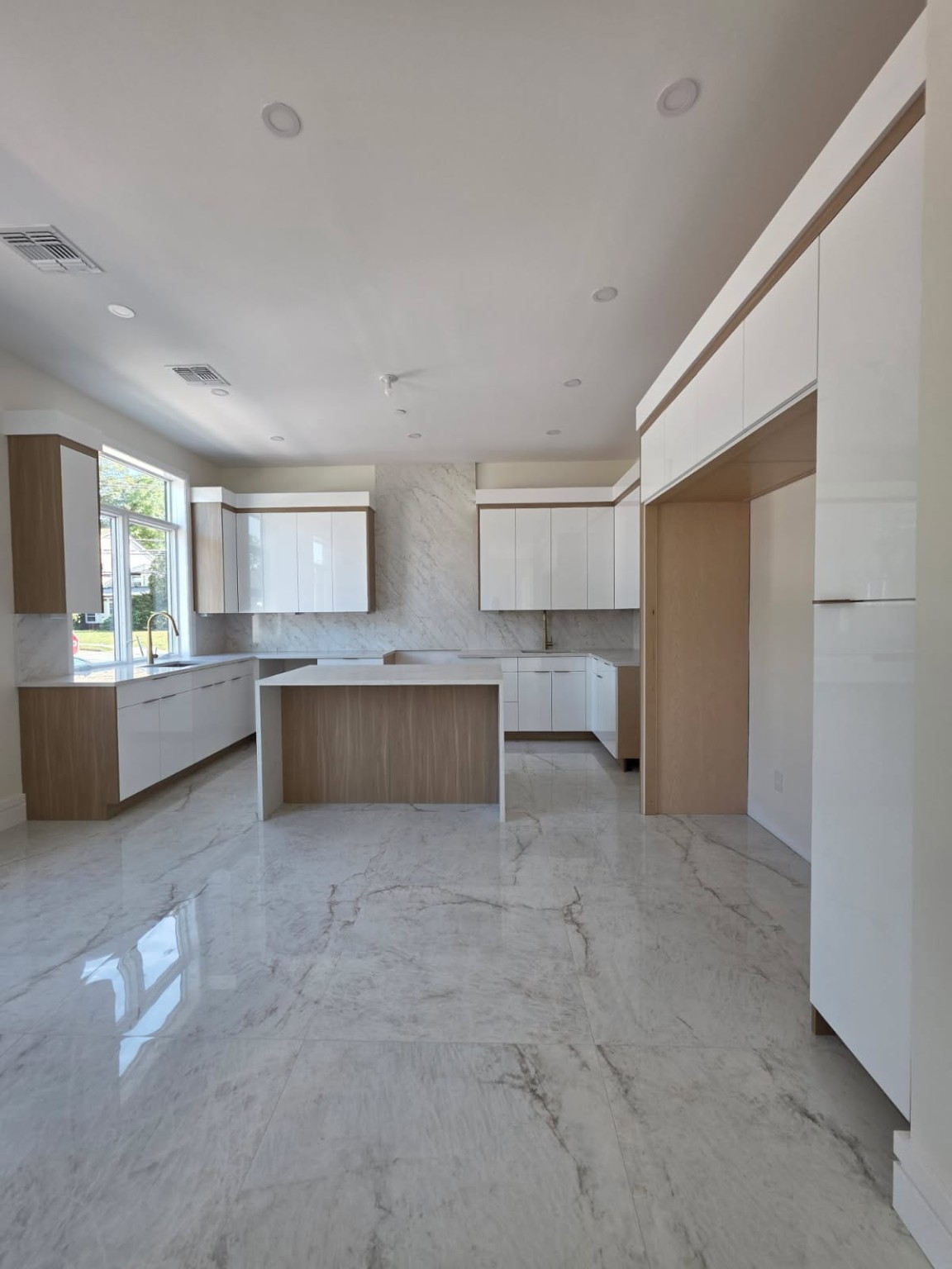 White and wood kitchen with an island and a full-height veined backsplash